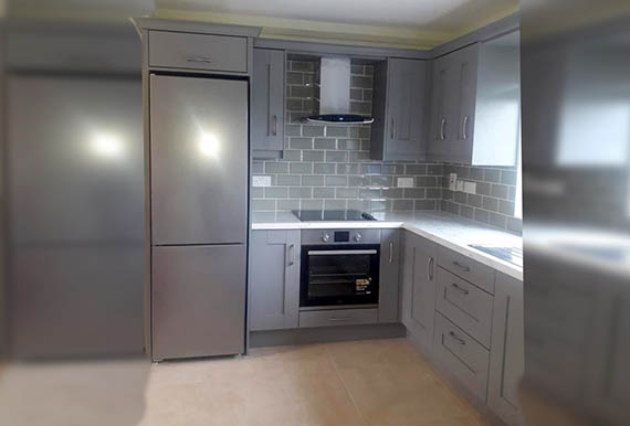 Light grey fitted kitchen with white worktops Image